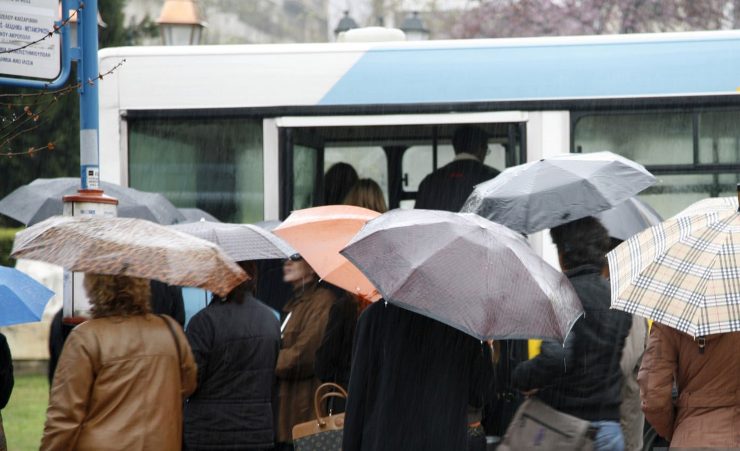 Persone con l'ombrello apsettano di salire sull'autobus